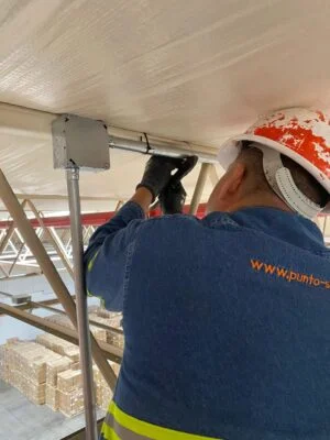 Técnico instalando enlace inalámbrico en nave industrial