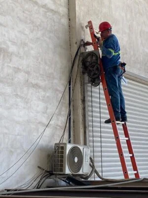 Técnico en escalera realizando instalación eléctrica exterior